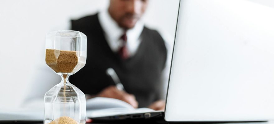 Businessman at desk with hourglass indicating time management and daily work routine.
