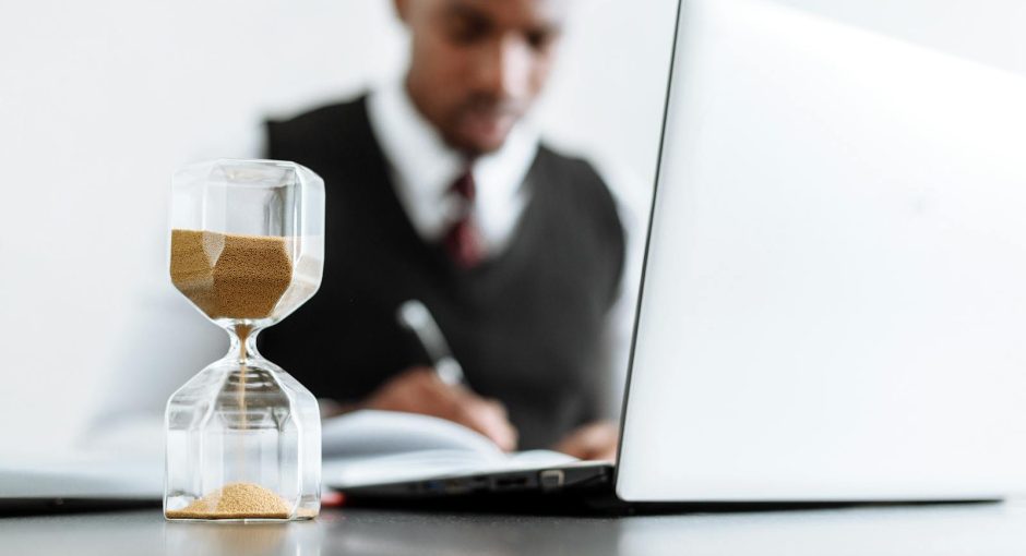 Businessman at desk with hourglass indicating time management and daily work routine.