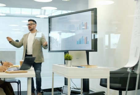 Man presenting data on a large screen to colleagues.