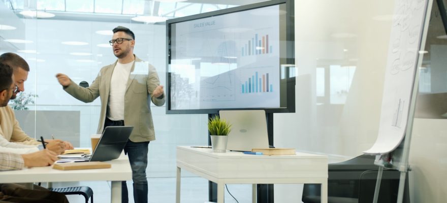Man presenting data on a large screen to colleagues.