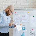 Business person in an office reviewing financial documents on a whiteboard.