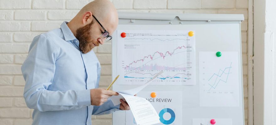 Business person in an office reviewing financial documents on a whiteboard.