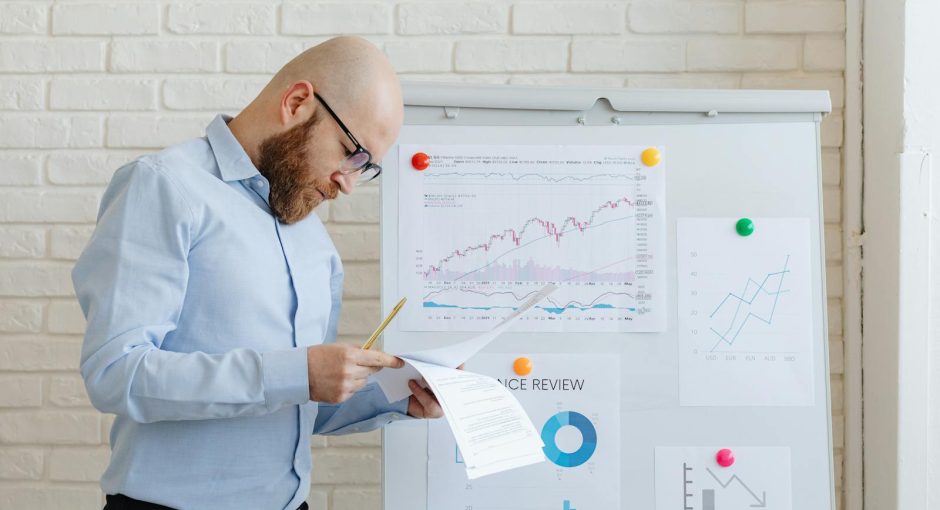 Business person in an office reviewing financial documents on a whiteboard.