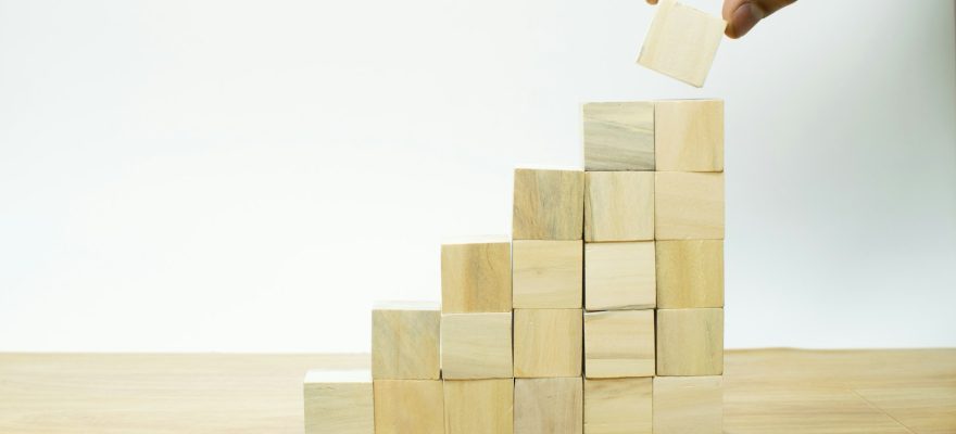 A person placing a piece of wood into a pyramid