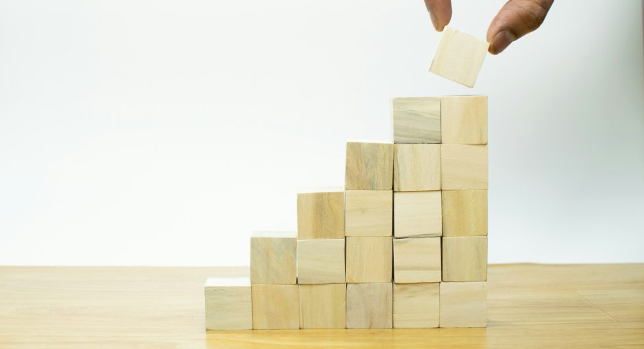 A person placing a piece of wood into a pyramid